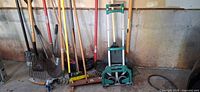 Group of yard tools and hand truck leaning against wall