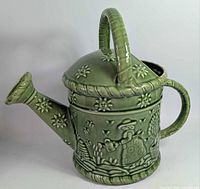 Full view of green ceramic watering can showing overall design