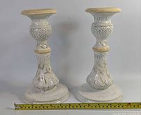 Full view of both matching ceramic candlesticks beside tape measure showing overall design and size