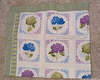 Full view of cotton tablecloth showing hydrangea panel design and gingham border