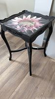 Full view of black side table showing resin flower top and legs
