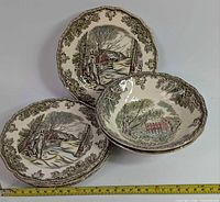 five side plates and two bowls showing pattern and border with tape for scale