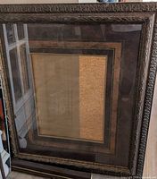Full view of large carved wood frame with glass and matting
