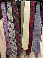 Seven assorted ties hanging on rack showing patterns and colours