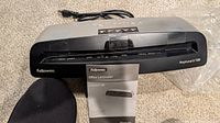 Front view of Fellowes Neptune3 125 laminator with power cord and manual visible