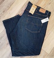 Folded jeans showing rear pocket, leather patch, hang tag