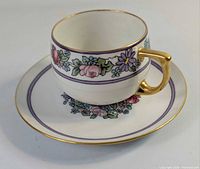 Cup on saucer front view showing floral band and gilt details