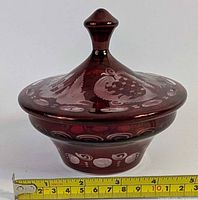 Overall view of Egermann ruby red cut-to-clear lidded candy dish with measuring tape for scale