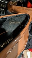 Interior branding and material tag of brown patent loafer