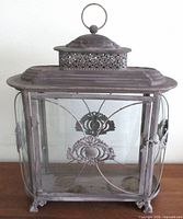 Front view of footed metal and curved glass terrarium lantern