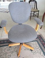 Front view of upholstered swivel chair showing seat, back, arms and wood base on casters