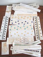 Overview of numerous metallic temporary tattoo strips on table
