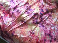 Full view of folded satin fabric showing abstract multicolor print