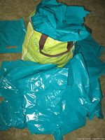Pile of turquoise plastic bags with die-cut handles spilling from a larger bag