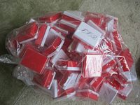 Large clear bag filled with numerous identical white/red hinged boxes