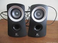 Front view of both Logitech speakers showing drivers, ports and logo