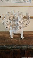 Front view of ceramic elephant candelabra showing candle cups and floral details