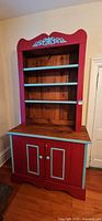 Front view of red and aqua two-piece hutch showing shelves and cabinet doors
