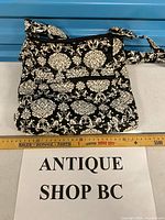 Full view of quilted black and white crossbody bag with ruler for scale