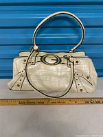 Front view of white faux croc Guess handbag with ruler for scale
