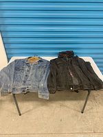 Both denim jackets laid flat on table