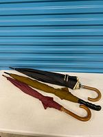 All three folded umbrellas side-by-side showing handles and colors