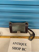 Front view of structured shoulder bag with chain strap and decorative clasp