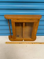 Front view showing full cabinet, glass door, knob, dividers, and ruler for scale