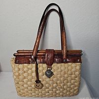 Full front view of woven straw handbag with leather trim and handles
