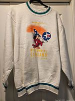 Full view of sweatshirt on hanger showing front graphic and ribbed trims