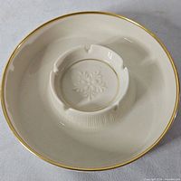 Top view showing ivory ashtray, gold rim, central cigarette rests and embossed rosette