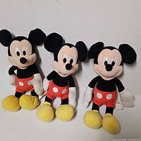 Three Mickey Mouse plush dolls standing upright