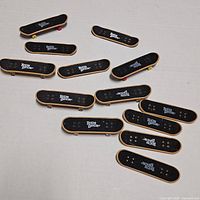 Thirteen fingerboards tops showing Tech Deck grip tape
