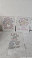 Three iron-on transfers standing upright showing graphics