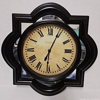 Front view of Sterling & Noble wall clock showing frame shape, dial, and mirrored accents