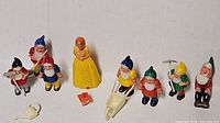 Group view of Snow White, seven dwarfs, wheelbarrow, watering can, red accessory