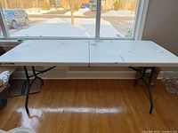 Full view of 6ft white folding table in front of window