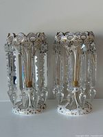 front view of both mantle lustres showing white glass, gilding and crystal prisms