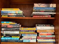 Two shelves filled with assorted hardcover and paperback books on varied subjects