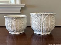 Front view of both jardinières showing size difference and leaf pattern