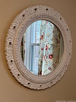 Full view of white ornate round mirror on wall