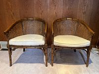 Front view of both matching faux bamboo barrel-back armchairs showing cane panels and cushions