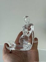 Front view of clear crystal mermaid figurine in hand