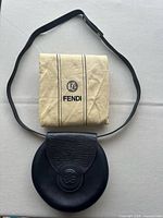 Bag with strap laid around folded Fendi dust sleeve