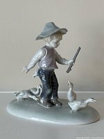Front view of Metzler Ortloff porcelain figurine showing boy, stick and three ducks