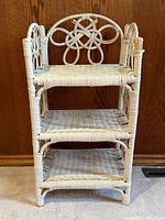 full view of white painted rattan shelf showing three tiers and decorative back