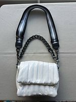 front view of white quilted patent Think Royln Bar Bag with chain and web straps attached