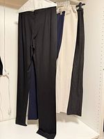 Four pairs of pants hanging: black, navy, cream, dark grey