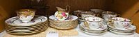 Cabinet shelf showing plates, teacups, saucers, creamer