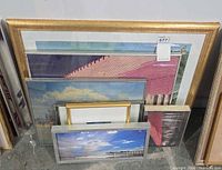 Stacked framed artwork showing several pieces including red pier photo and panoramic seascape